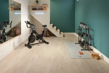 Coretec Residential SPC LVP Flooring in Home Gym - 49x7.13 inch Home gym with exercise bike and weights on Coretec Residential SPC luxury vinyl plank flooring in a wood look