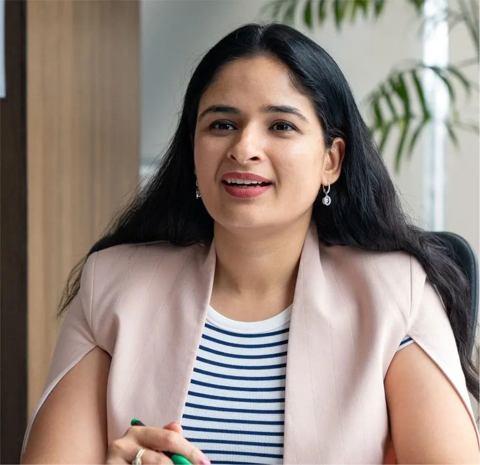 Woman in a professional setting with a striped shirt and light pink blazer