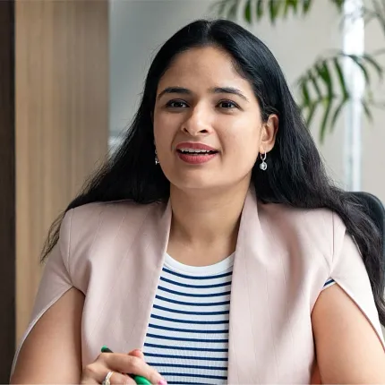 Professional woman in office attire with striped shirt and pink blazer Woman in a professional setting with a striped shirt and light pink blazer