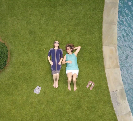 Ladies laying on turf beside pool