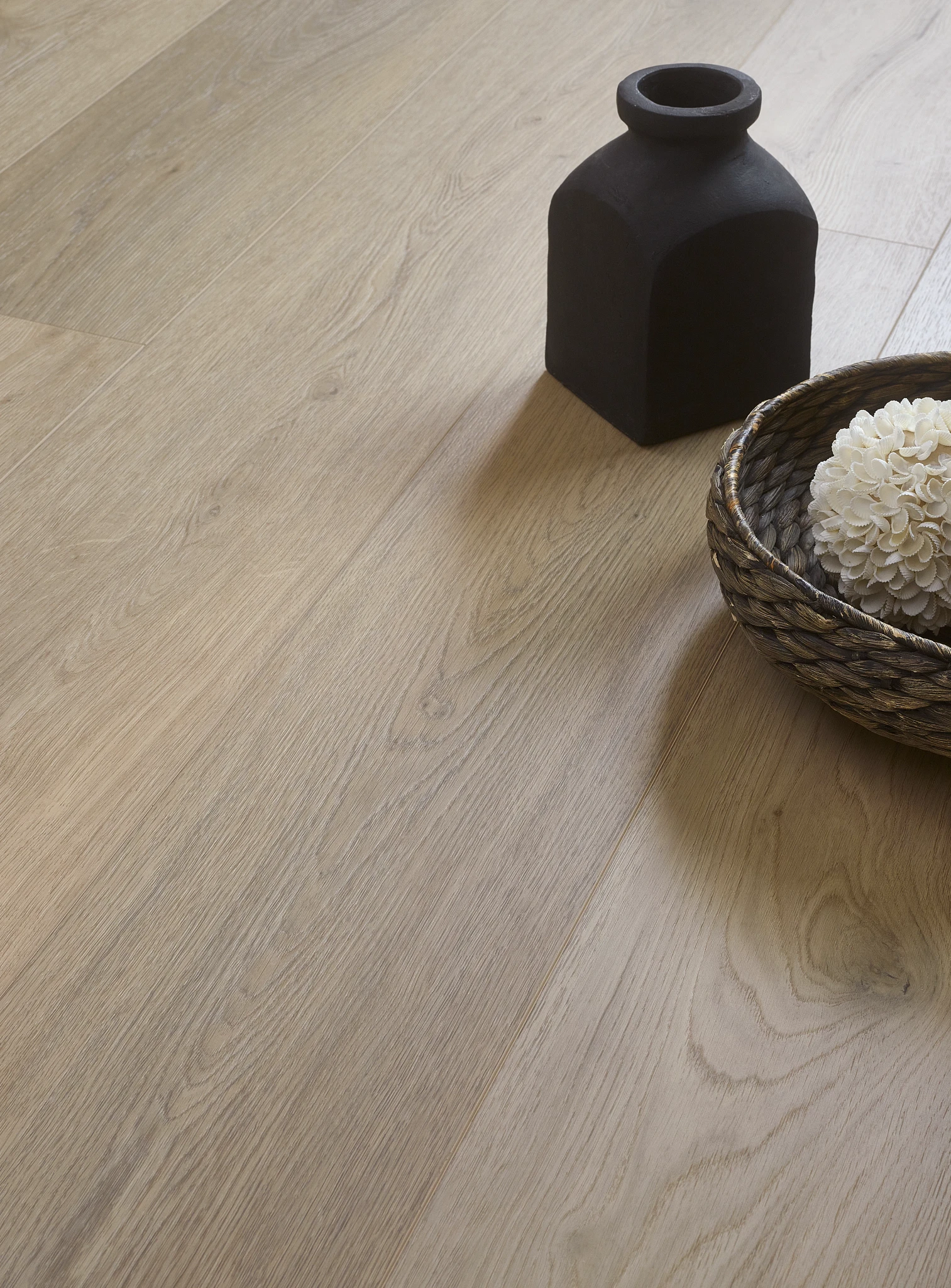 Light oak wood look luxury vinyl plank flooring with decorative vase and basket