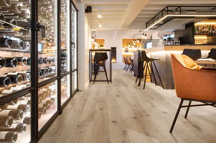Wood Look Luxury Vinyl Plank Flooring in Modern Restaurant Interior Modern restaurant interior with wood look luxury vinyl plank flooring, featuring a wine display and stylish seating.
