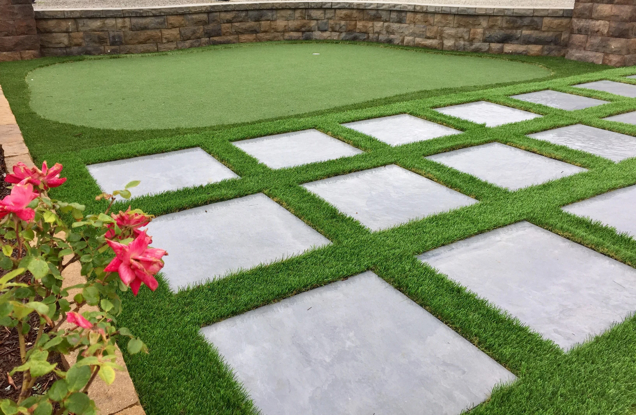 Outdoor patio with gray stone tiles and green artificial grass