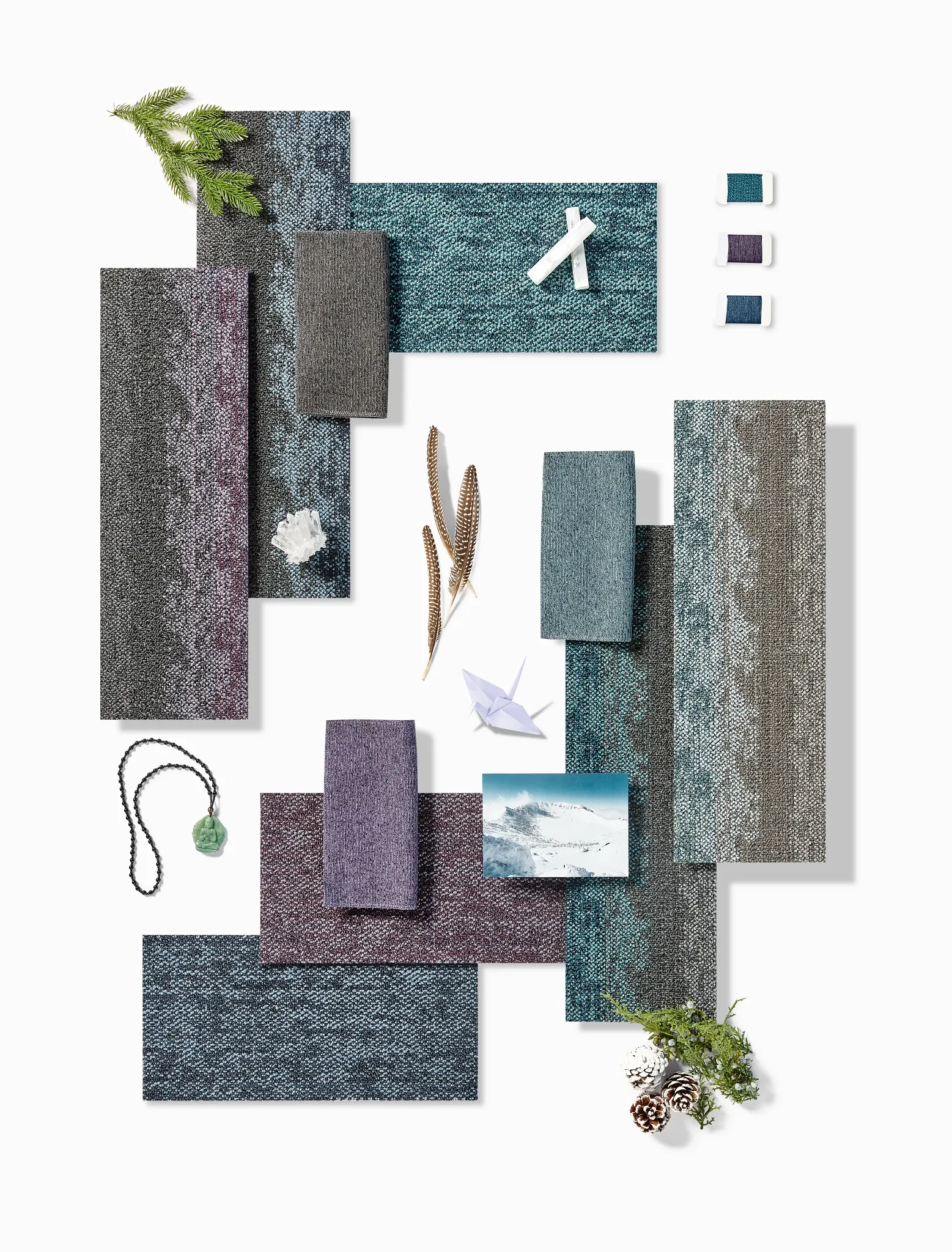 Assorted carpet swatches in shades of blue, purple, and black with natural elements and fabric samples on a textured surface