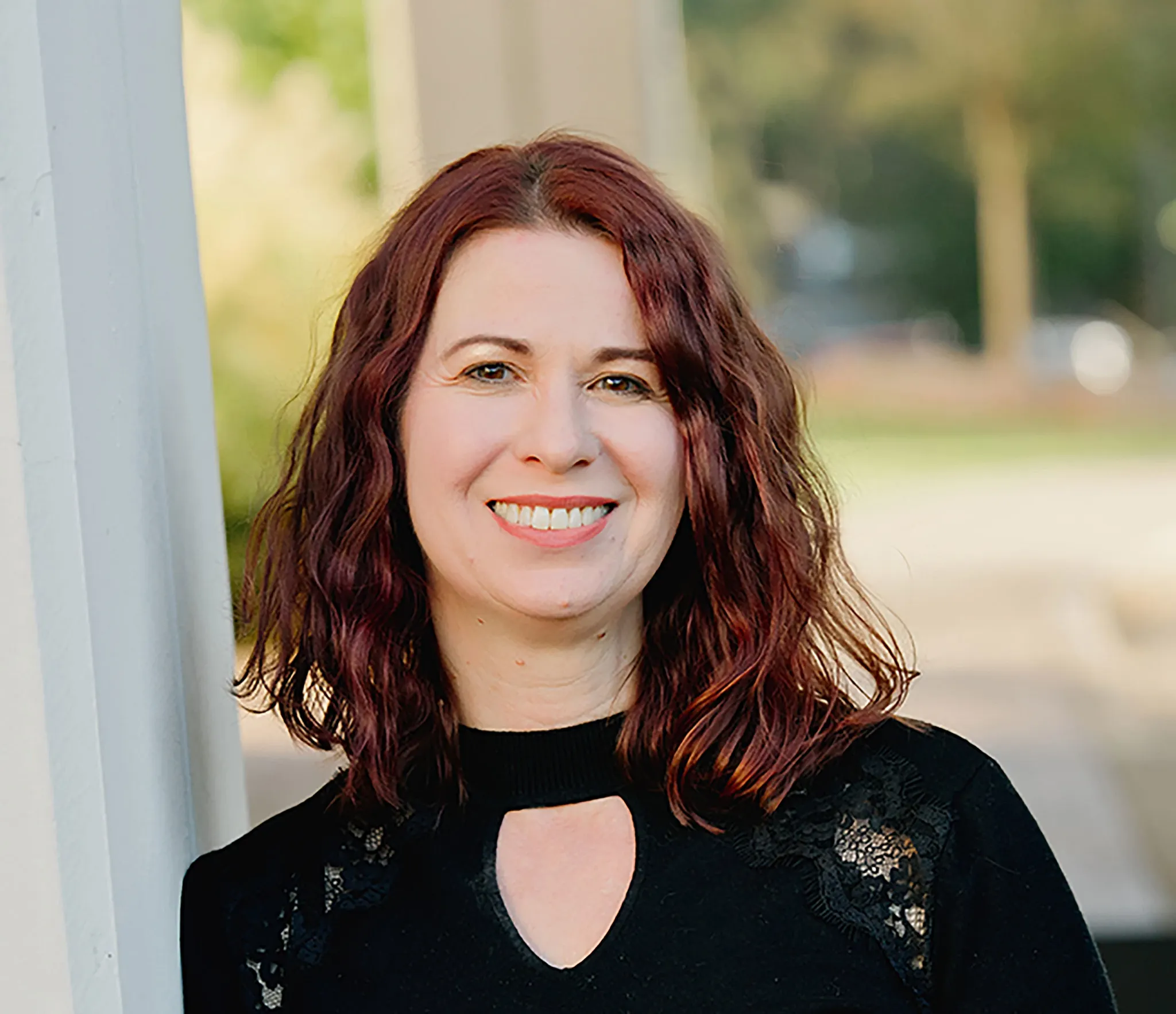 A business style headshot of a woman with red hair and black outfit