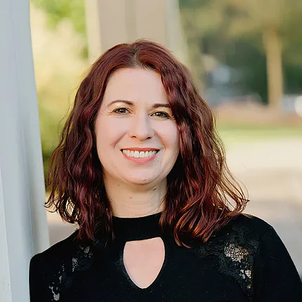 A business style headshot of a woman with red hair and black outfit