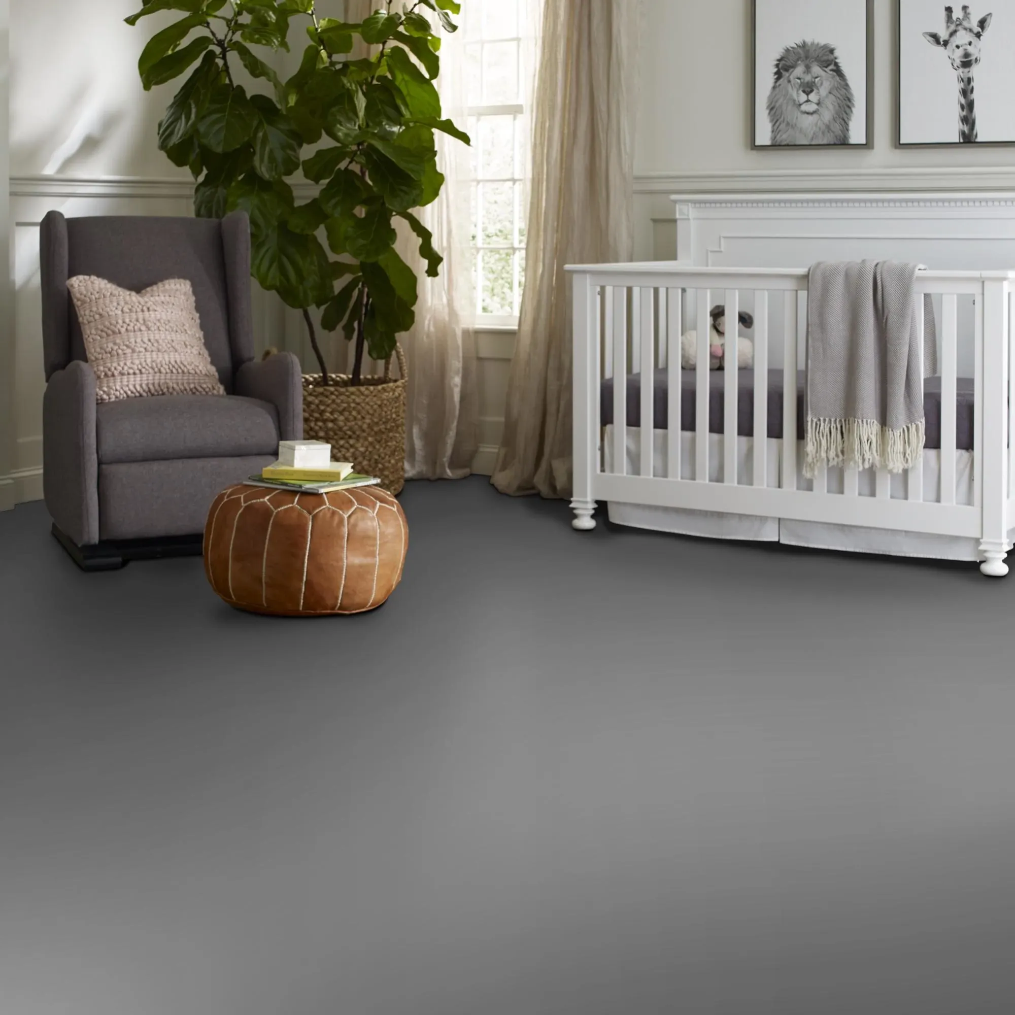 Modern nursery room with gray flooring, white crib, gray armchair, and brown ottoman