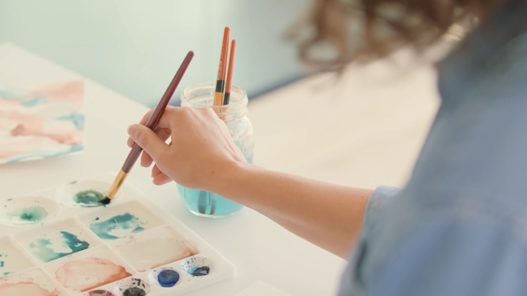 Woman painting with watercolor palette on a white table
