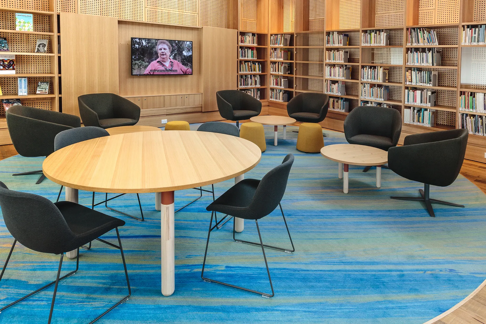 Collaborative learning space within the University of Tasmania library featuring custom blue patterned flooring, flexible seating and integrated book collections.