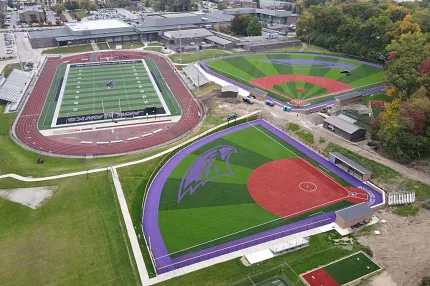 Sports complex with artificial turf fields and track. Aerial view of sports complex featuring artificial turf fields with purple and green designs