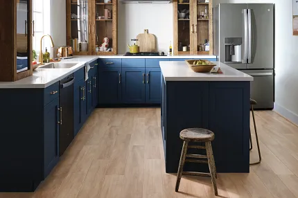Coretec Residential WPC Luxury Vinyl Plank Flooring in Modern Kitchen - 48.03x7.05 inch kitchen with luxury vinyl plank floor in a light wood look with blue cabinets and stainless steel appliances