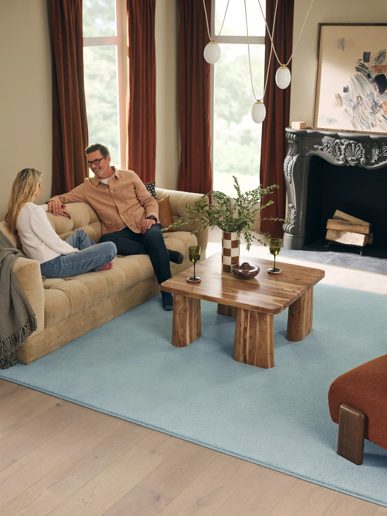 Living room with light blue synthetic carpet, beige sofa, wooden coffee table, and fireplace