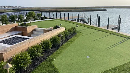 Residential artificial turf putting green with waterfront view Backyard putting green overlooking waterfront dock and marsh landscape