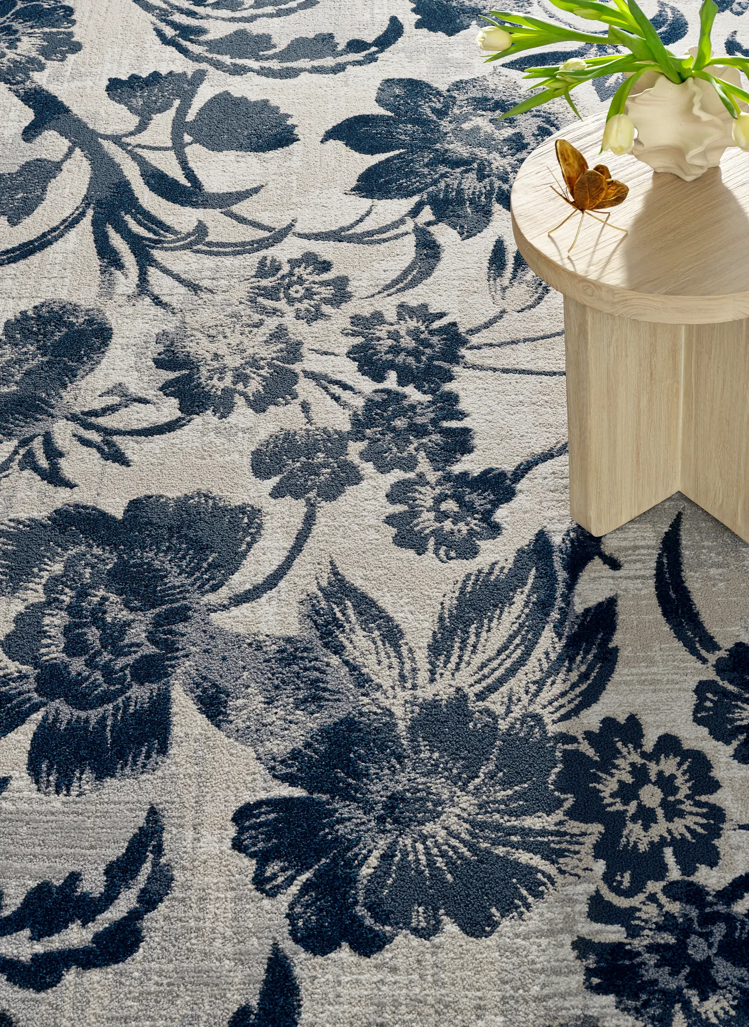 Floral patterned carpet in navy and beige with wooden table and white flowers