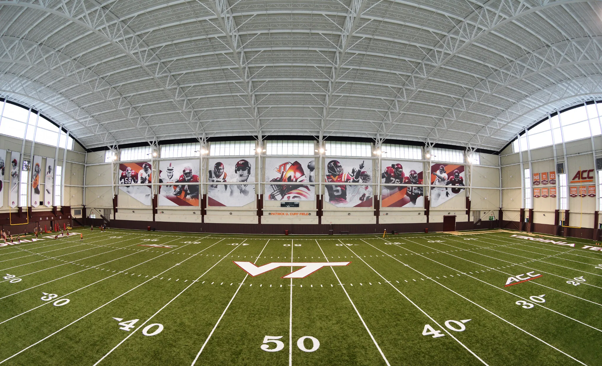 Indoor sports facility with artificial turf field and large sports-themed wall banners