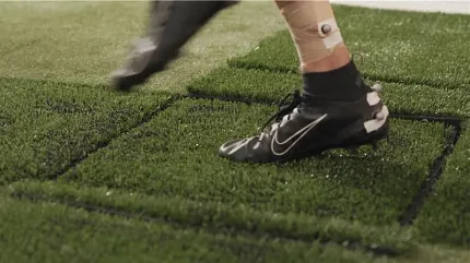 Black Nike cleats on artificial grass surface Person wearing black Nike soccer cleats stepping on artificial turf