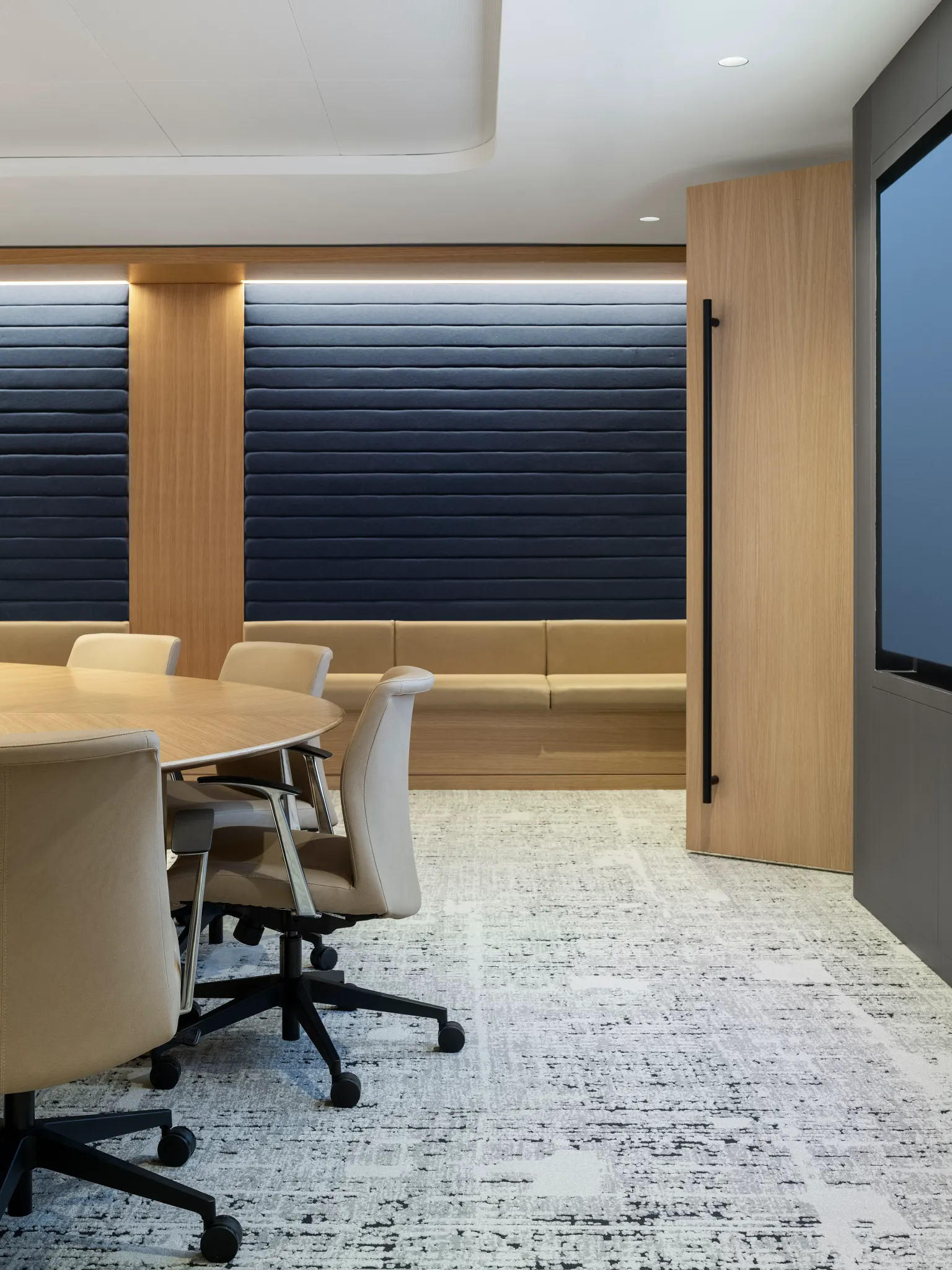 Modern conference room with beige chairs and a round table on a commercial broadloom carpet