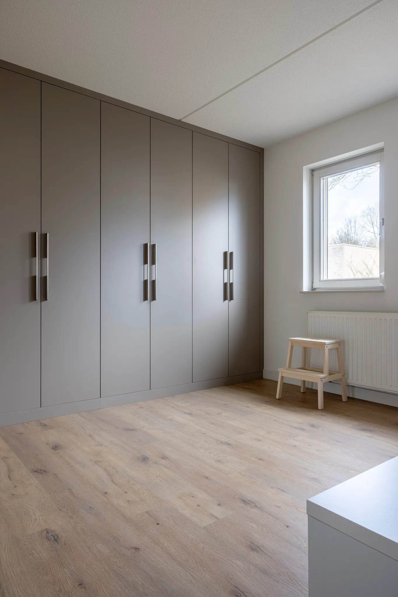 Light oak flooring in a modern minimalist room with grey cabinets