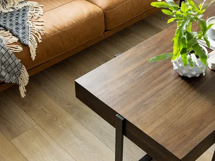 Contemporary living room with light oak flooring and stylish decor Modern living room with light oak wood flooring, brown leather sofa, and wooden coffee table with green plant