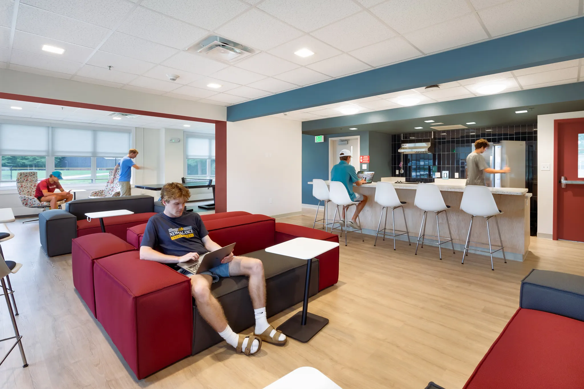 Education facility lounge with young adults using laptops, featuring COREtec multilayer SPC flooring with acoustic backing in 48.03x6.92 inch dimensions