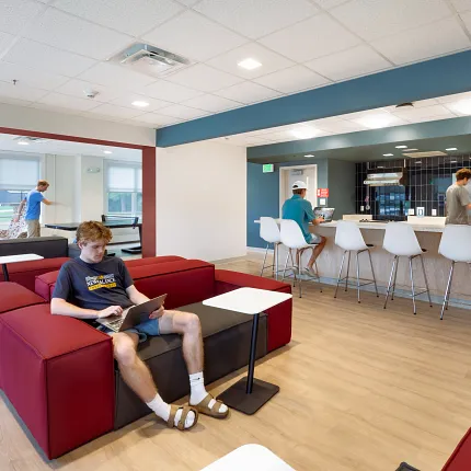 Education Facility Lounge with COREtec SPC Flooring Education facility lounge with young adults using laptops, featuring COREtec multilayer SPC flooring with acoustic backing in 48.03x6.92 inch dimensions