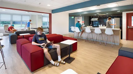 Education Facility Lounge with COREtec SPC Flooring Education facility lounge with young adults using laptops, featuring COREtec multilayer SPC flooring with acoustic backing in 48.03x6.92 inch dimensions