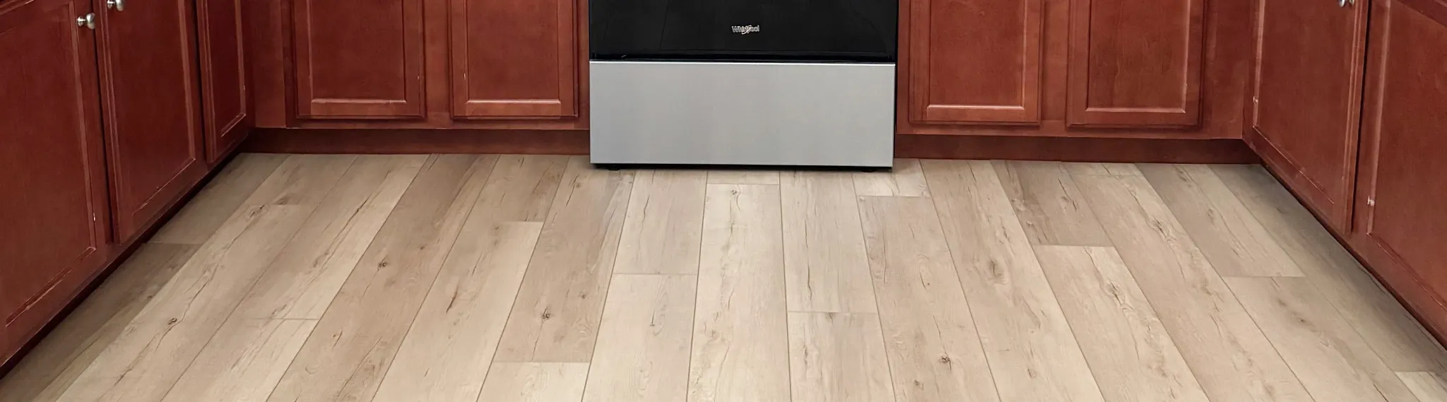 Modern kitchen with light wood look luxury vinyl plank flooring and cherry wood cabinets