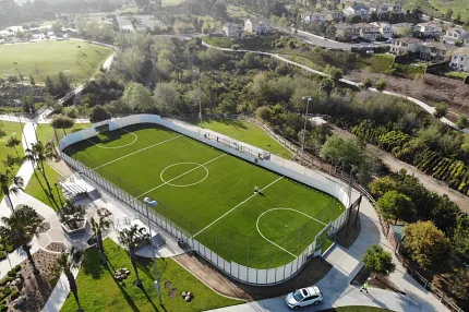 Artificial Turf Soccer Field in Residential Area Aerial view of a soccer field with artificial turf surrounded by residential area and greenery