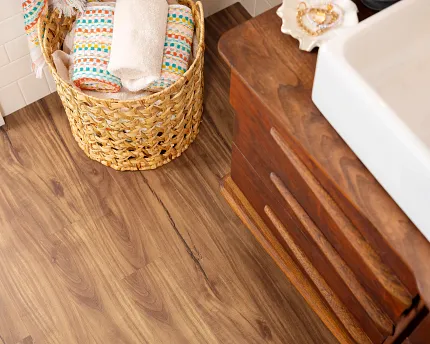 Coretec Residential WPC Luxury Vinyl Plank Flooring in Bathroom Scene Bathroom scene with Coretec Residential WPC luxury vinyl plank flooring in a wood look, featuring a basket with colorful towels and a wooden vanity, dimensions 48.03x4.96 inch