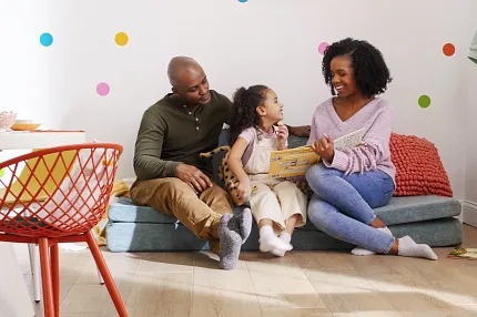 Light Wood Look Luxury Vinyl Plank Flooring in a Family Room Scene Family sitting on a sofa in a colorful room with light wood look luxury vinyl plank flooring