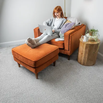 woman sitting on an orange arm chair with plush gray carpet visible woman sitting on an orange arm chair with plush gray carpet visible