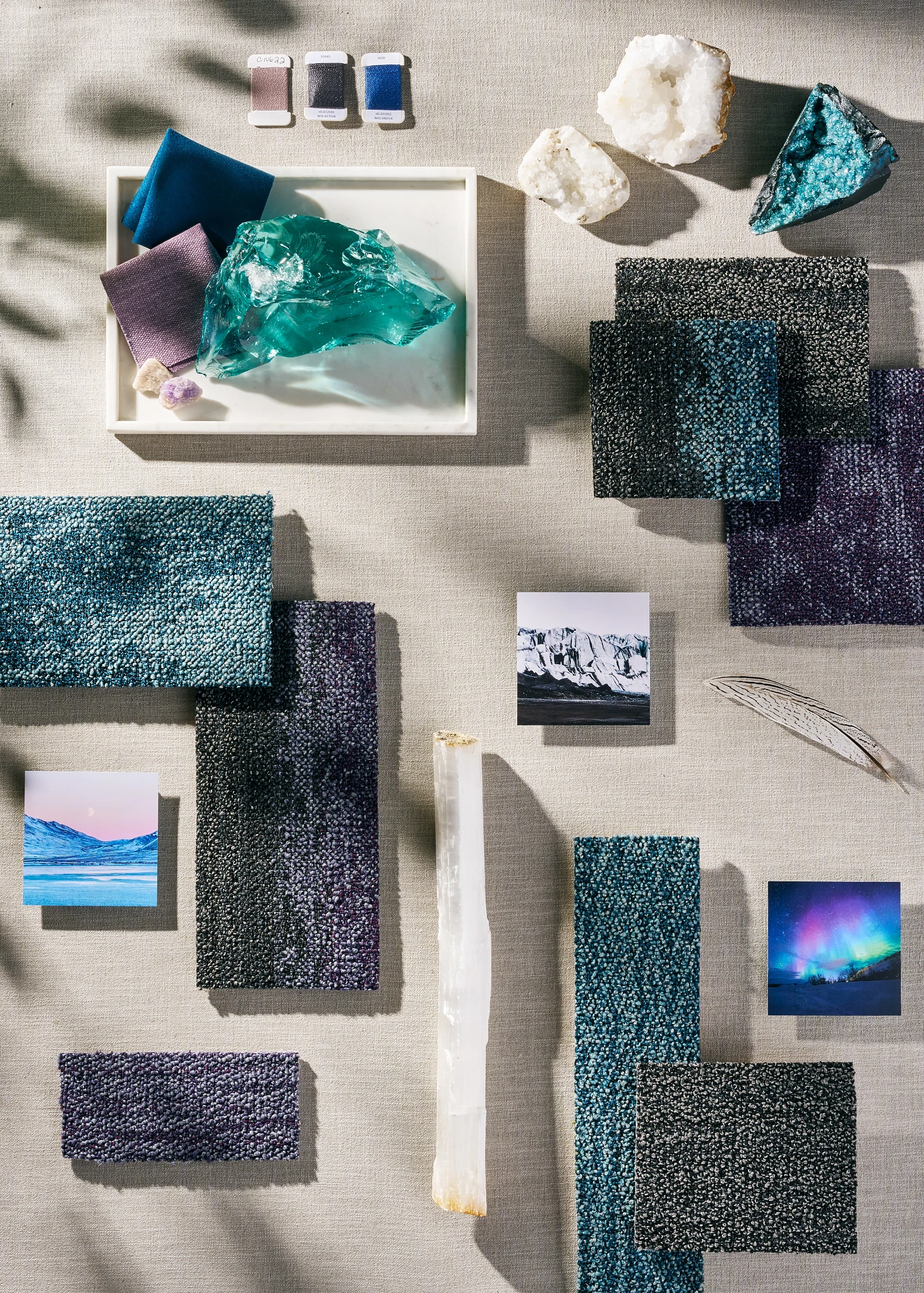 Assorted carpet swatches in shades of blue, purple, and black with natural elements and fabric samples on a textured surface