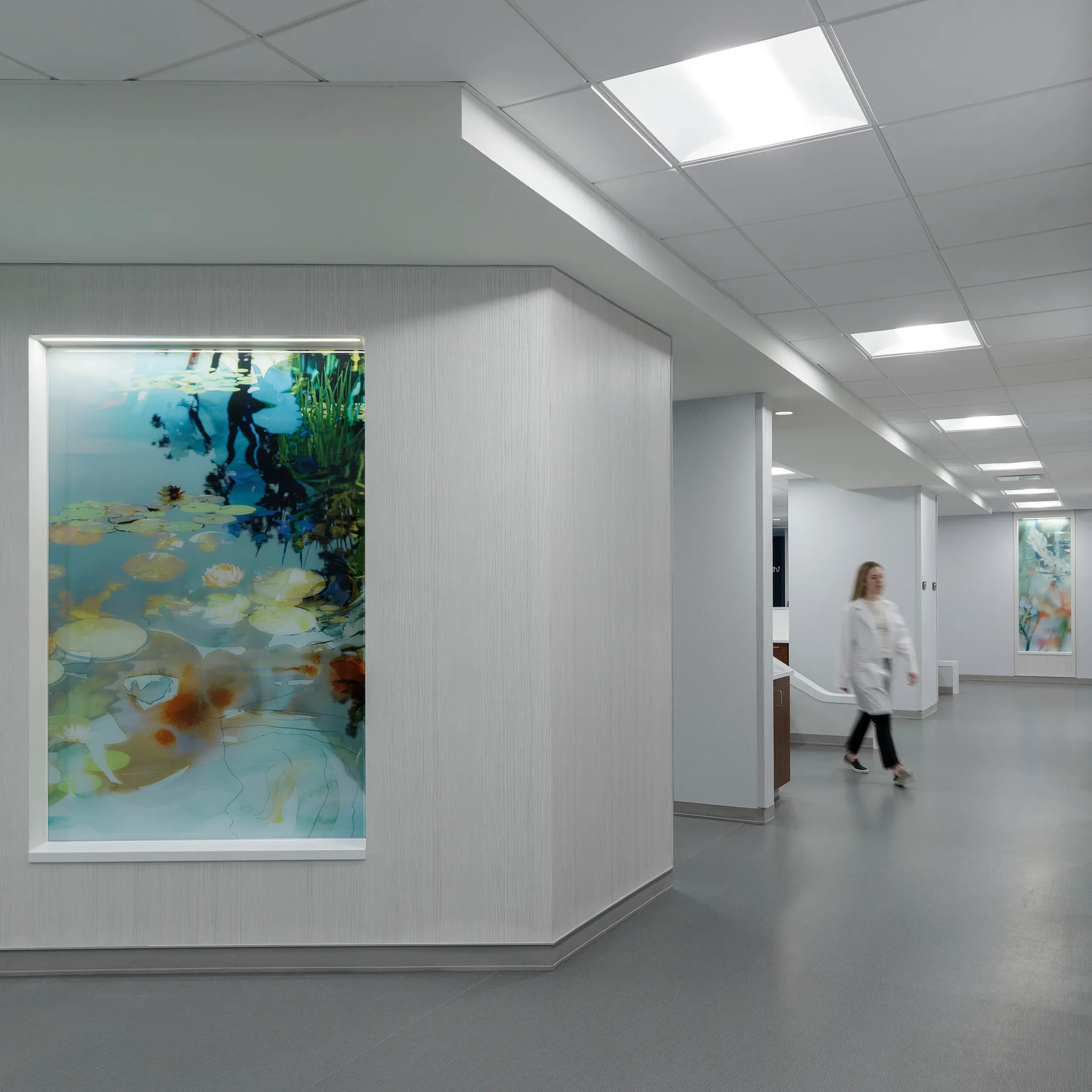 Modern healthcare facility hallway with gray flooring and abstract wall art
