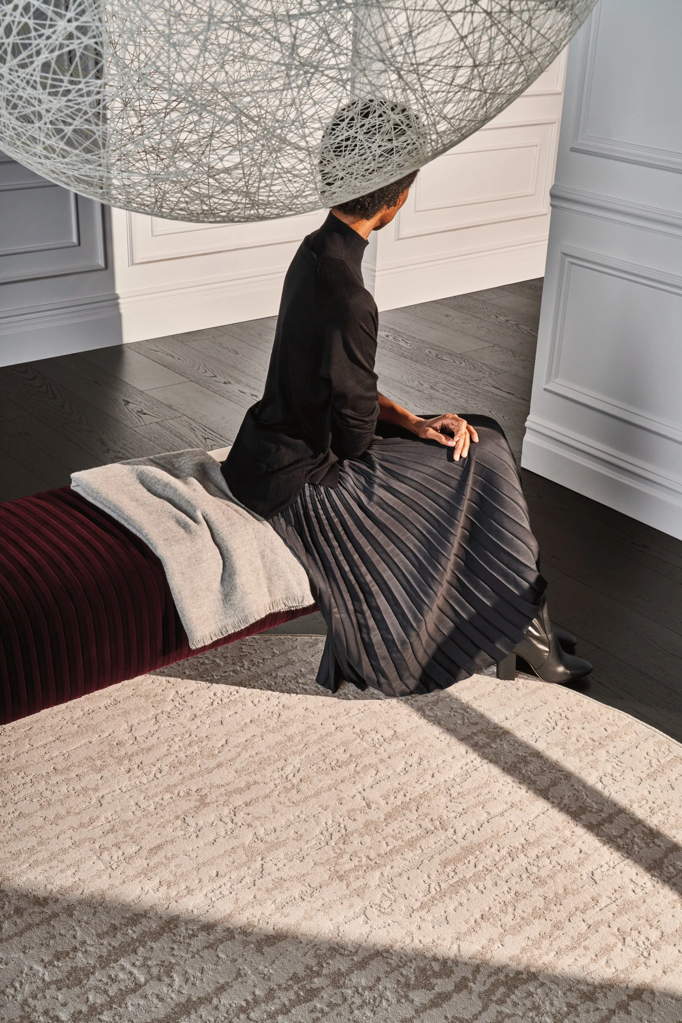 Woman sitting on a bench in a luxurious room with textured beige carpet flooring