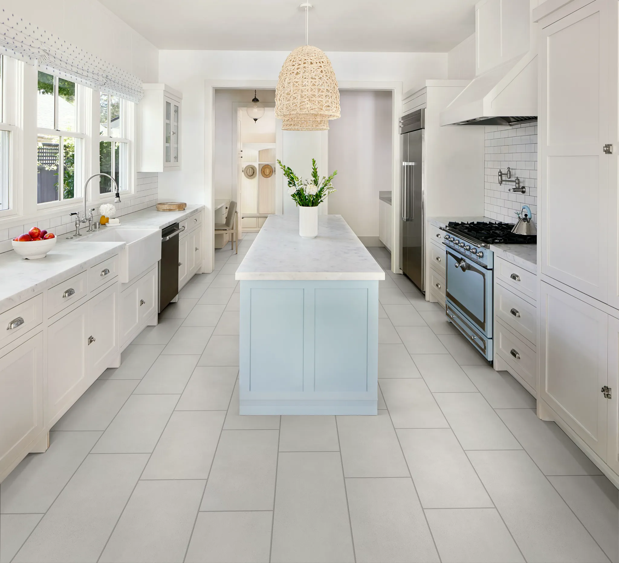 Modern kitchen with light gray tile flooring, white cabinetry, and a blue island