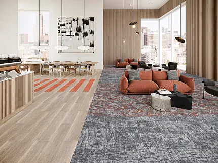 Contemporary office space with mixed flooring design in orange and gray tones Modern office lounge with a mix of light wood flooring and patterned carpet tiles, featuring orange and gray tones