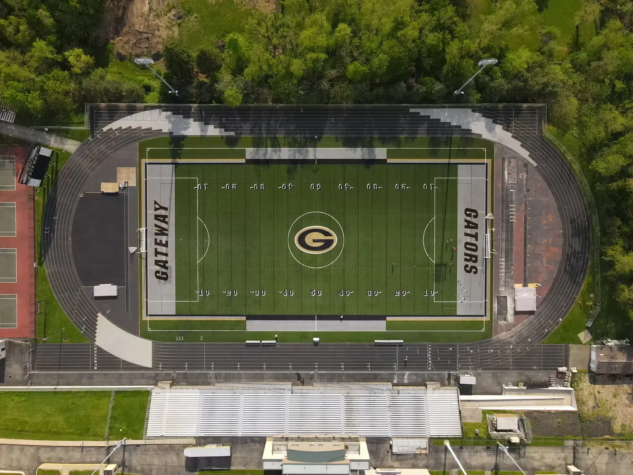 Aerial view of a football field with track and surrounding greenery