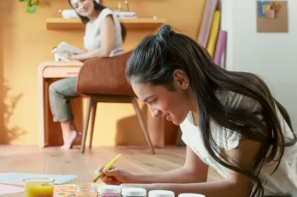 Luxury Vinyl Plank Flooring in Modern Living Room - Durable and Scratch-Resistant Wood Look Modern living room with luxury vinyl plank flooring featuring a young girl painting and a woman reading, showcasing a warm wood look and durable, scratch-resistant surface.