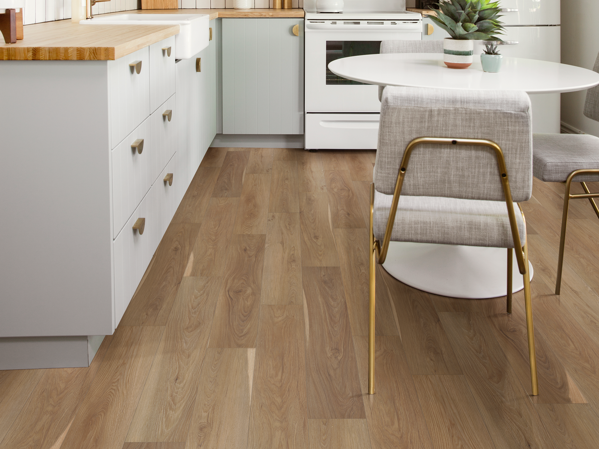 Modern kitchen with light gray cabinets, butcher block countertops, and white round dining table with upholstered chairs on Supino HD Natural Bevel flooring in Jasper, showcasing warm wood tones and a smooth matte finish.