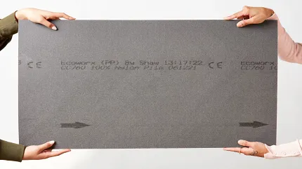 Durable EcoWorx carpet swatch for sustainable flooring solutions Two people holding a grey carpet swatch with EcoWorx backing