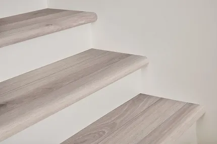 Durable and easy-to-maintain light wood laminate flooring for stairs Light wood laminate flooring on staircase with white risers