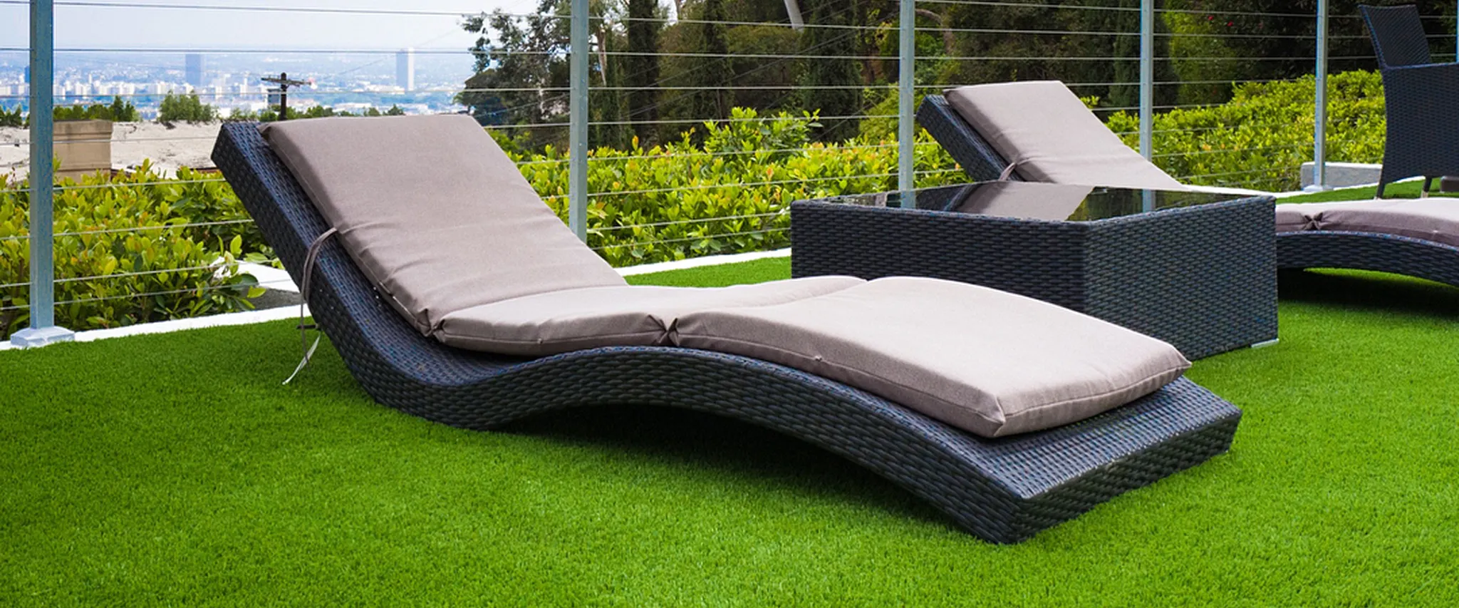 Outdoor lounge chairs on artificial grass with city view