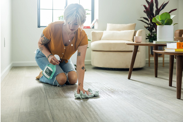 A young woman cleaning a luxury vinyl floor in a living room