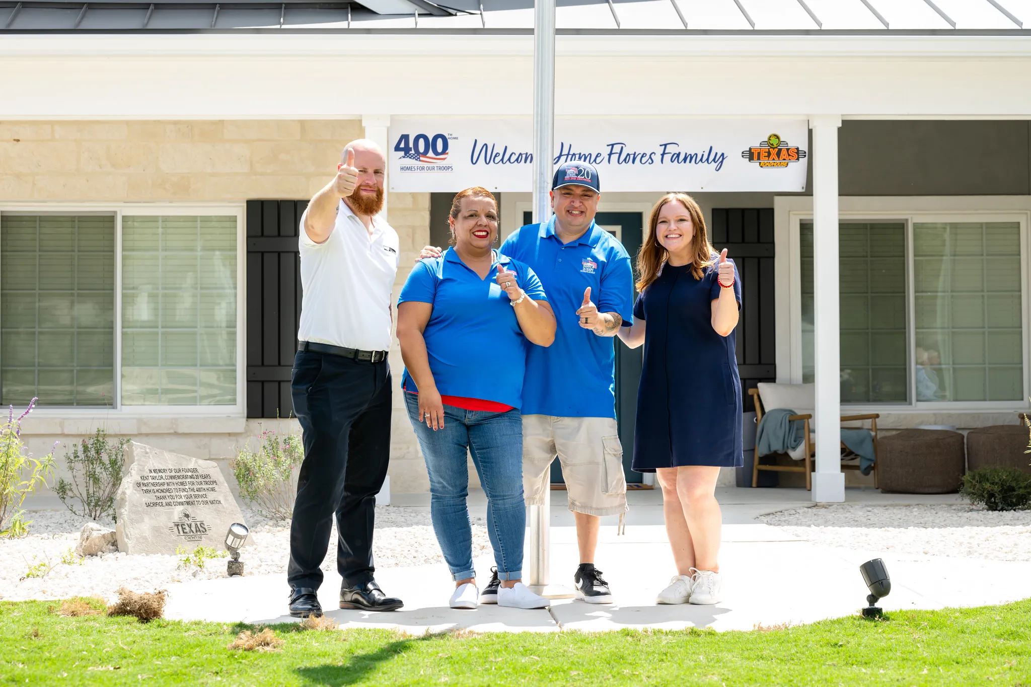 Group of people standing in front of a modern residential building with a welcoming banner