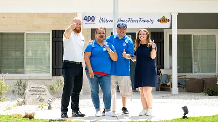 Modern residential building with welcoming banner and group of people. Group of people standing in front of a modern residential building with a welcoming banner