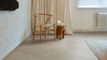 Light Wood Look Luxury Vinyl Plank Flooring in Modern Living Room Scene Modern living room with light wood look luxury vinyl plank flooring, featuring a wooden chair and side table with candles
