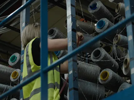 Commercial Carpet Production Facility with Worker and Machinery Industrial carpet manufacturing process with machinery and worker inspecting fabric
