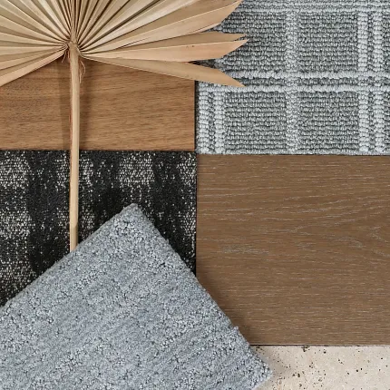 Carpet and Hardwood Flooring Swatches with Neutral Tones Carpet and hardwood flooring swatches with beige, gray, and brown tones alongside a decorative dried palm leaf