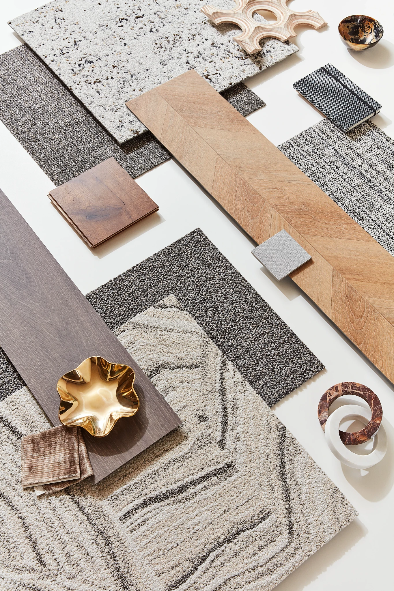 Flooring design palette featuring light and dark wood planks, textured carpet swatches in gray and beige tones, and decorative elements