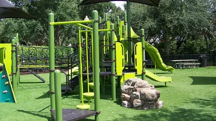 Durable artificial grass for playgrounds Green playground equipment on artificial grass surface